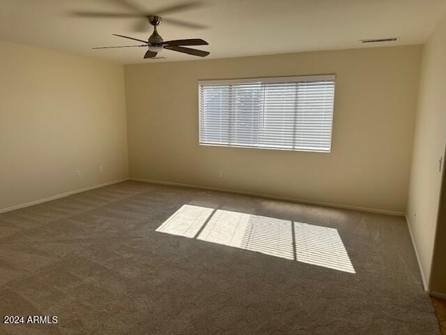 spare room featuring visible vents, carpet flooring, baseboards, and ceiling fan