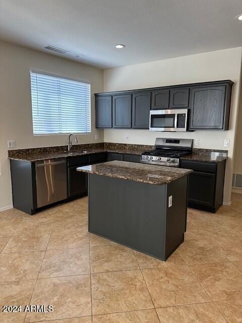 kitchen with visible vents, a center island, dark stone countertops, appliances with stainless steel finishes, and a sink