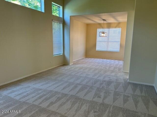 carpeted spare room with baseboards and a towering ceiling