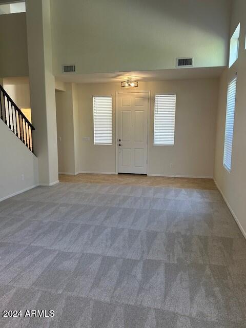 interior space featuring visible vents, a high ceiling, and light colored carpet