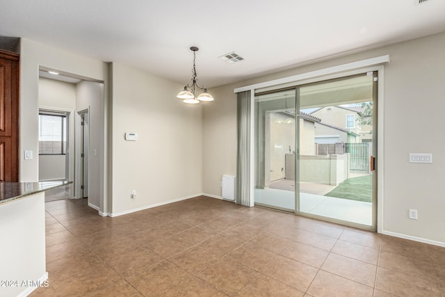 spare room with an inviting chandelier, tile patterned floors, and a wealth of natural light