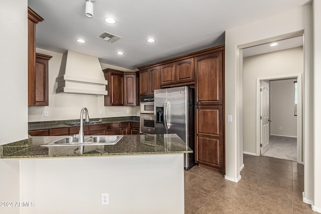 kitchen with premium range hood, stainless steel appliances, kitchen peninsula, and dark stone counters