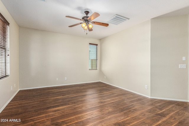 empty room with dark wood-type flooring, ceiling fan, and a wealth of natural light