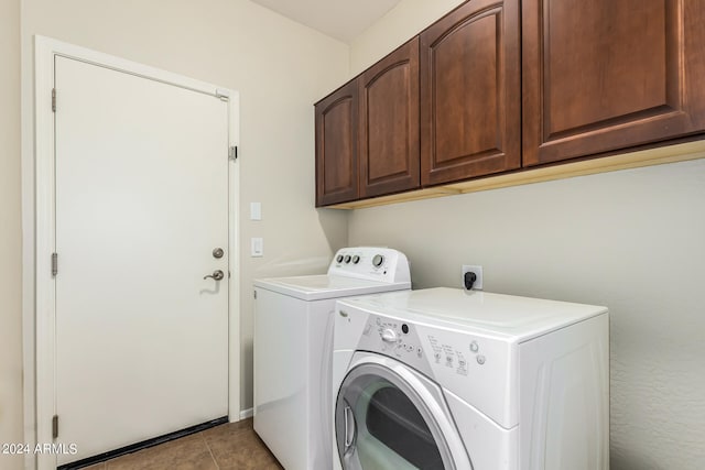 laundry room featuring light tile patterned floors, washing machine and clothes dryer, and cabinets