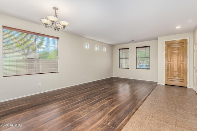 spare room with a notable chandelier and hardwood / wood-style floors