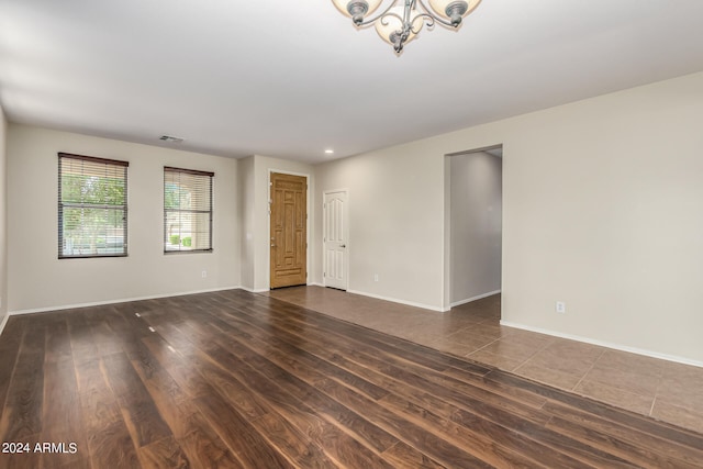 unfurnished room with a notable chandelier and dark wood-type flooring