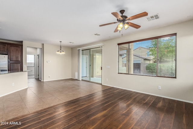 unfurnished living room with ceiling fan with notable chandelier and dark hardwood / wood-style floors