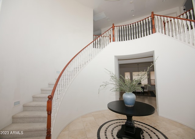 staircase featuring a high ceiling and tile patterned floors