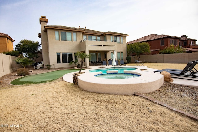 back of house featuring a balcony, a patio, and an in ground hot tub