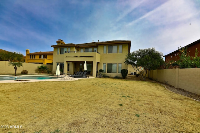 back of property with a yard, a patio, a fenced in pool, and a balcony