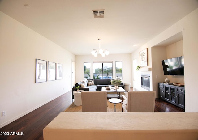 living room with dark wood-type flooring and an inviting chandelier