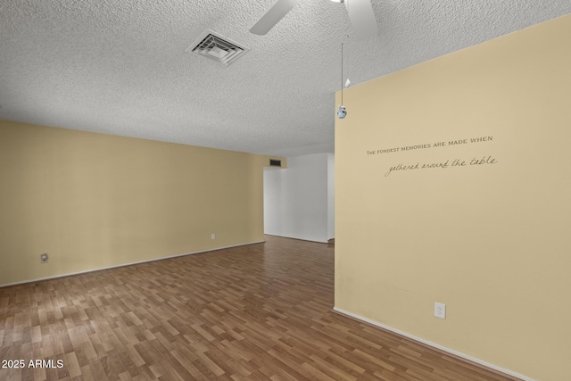 spare room with ceiling fan, a textured ceiling, wood finished floors, and visible vents