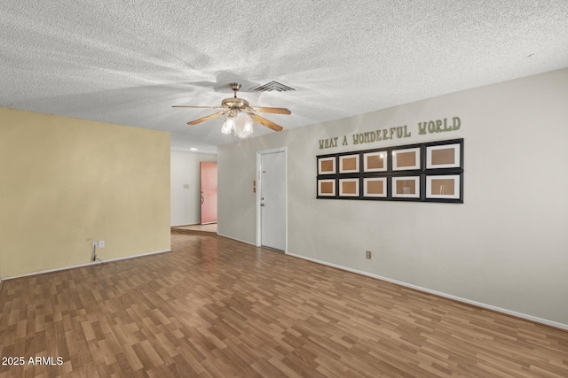 spare room with a ceiling fan, a textured ceiling, visible vents, and wood finished floors