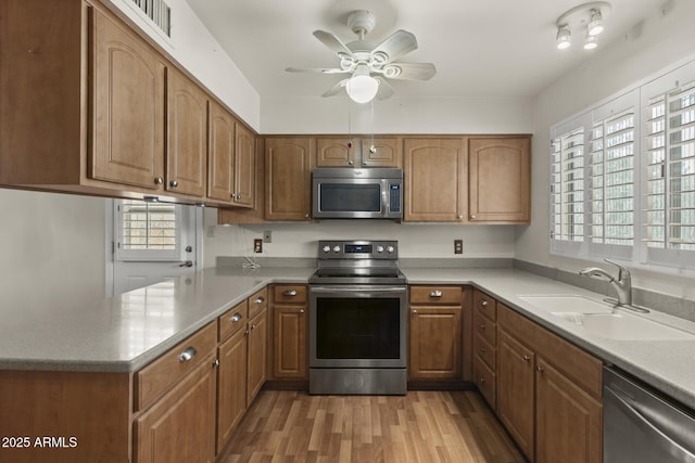 kitchen with light wood-type flooring, appliances with stainless steel finishes, plenty of natural light, and a sink