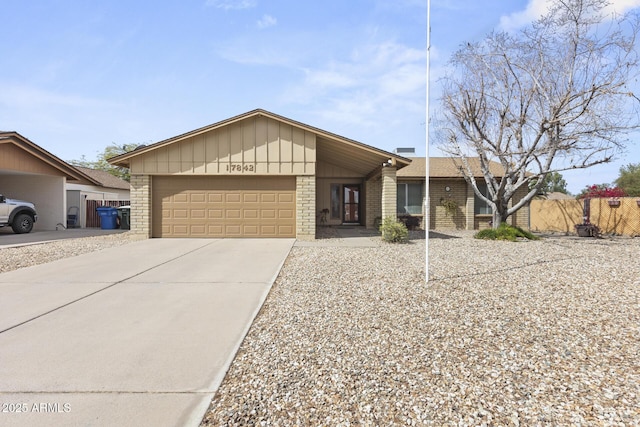 view of front of home with driveway, a garage, fence, and brick siding