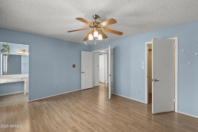 unfurnished bedroom featuring baseboards, a textured ceiling, visible vents, and wood finished floors