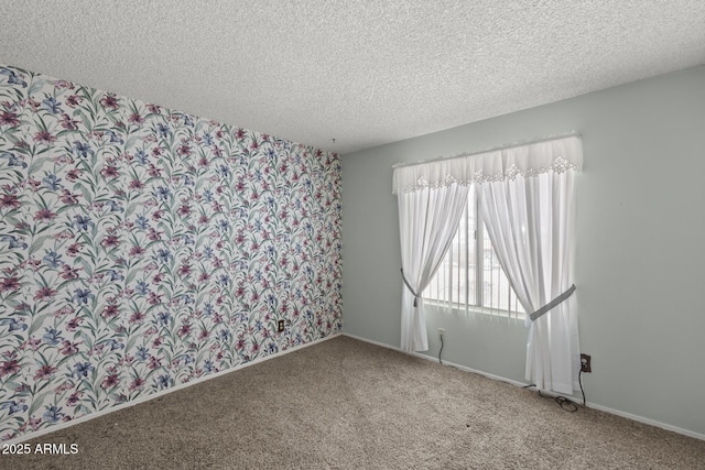 carpeted empty room with a textured ceiling and baseboards