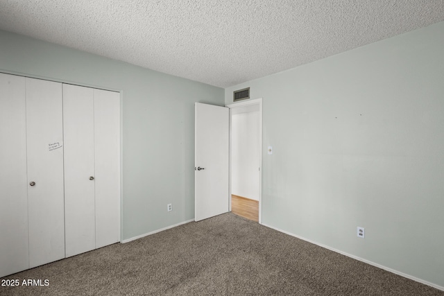 unfurnished bedroom featuring a textured ceiling, a closet, carpet, and visible vents