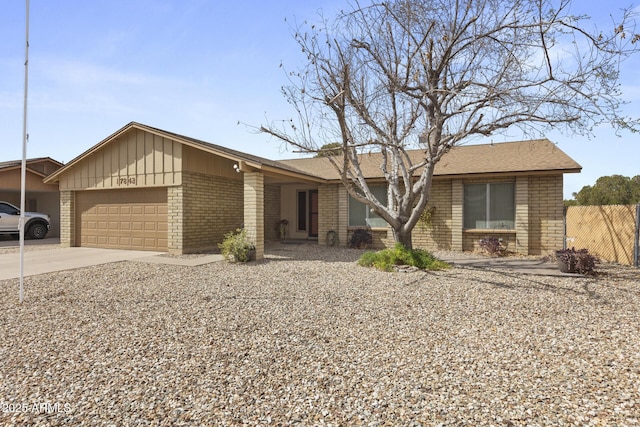 view of front of house featuring brick siding, concrete driveway, board and batten siding, fence, and a garage