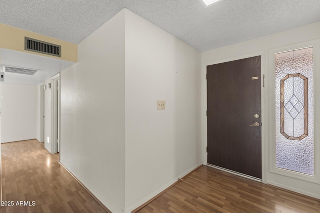 entryway featuring a wealth of natural light, visible vents, a textured ceiling, and wood finished floors