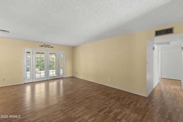 spare room with a textured ceiling, wood finished floors, and visible vents