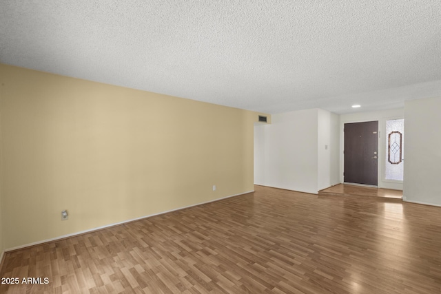 unfurnished room featuring a textured ceiling, wood finished floors, and visible vents