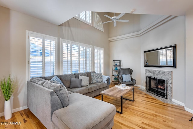 living area with light wood finished floors, a fireplace with flush hearth, a wealth of natural light, and baseboards