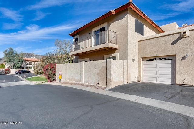 view of front of property featuring a garage, a tiled roof, a balcony, and stucco siding