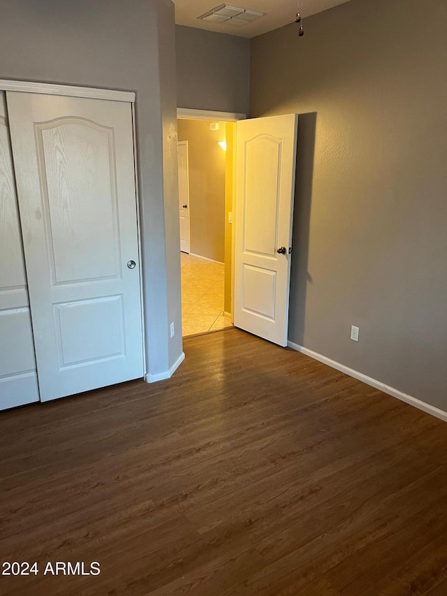 unfurnished bedroom featuring a closet and dark wood-type flooring