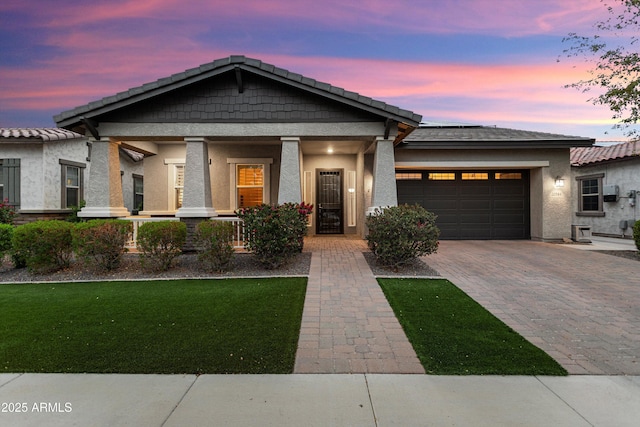 view of front facade featuring stucco siding, a front lawn, driveway, a porch, and a garage