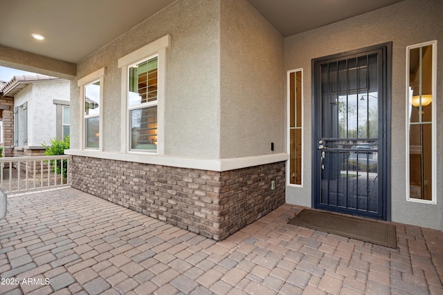 view of exterior entry with stone siding and stucco siding