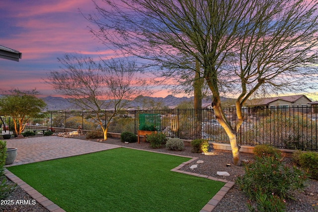 yard at dusk with a mountain view, a patio, and fence