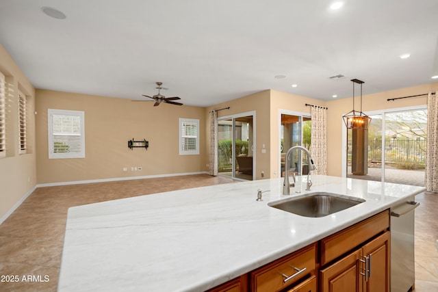 kitchen featuring brown cabinetry, open floor plan, hanging light fixtures, a ceiling fan, and a sink