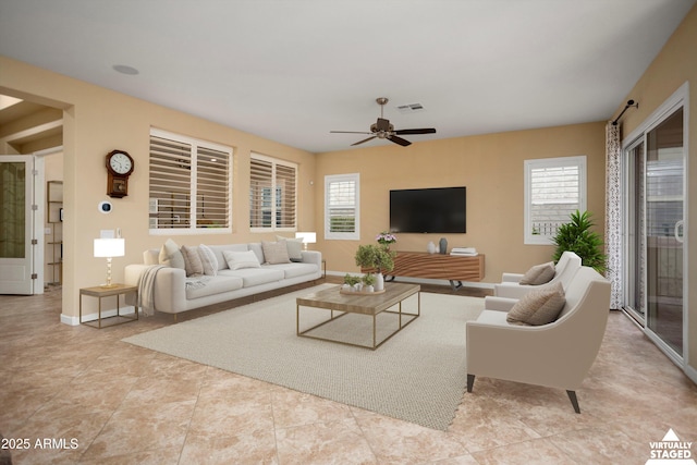 living area featuring visible vents, baseboards, and ceiling fan