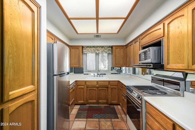 kitchen with light countertops, electric range, a sink, and freestanding refrigerator