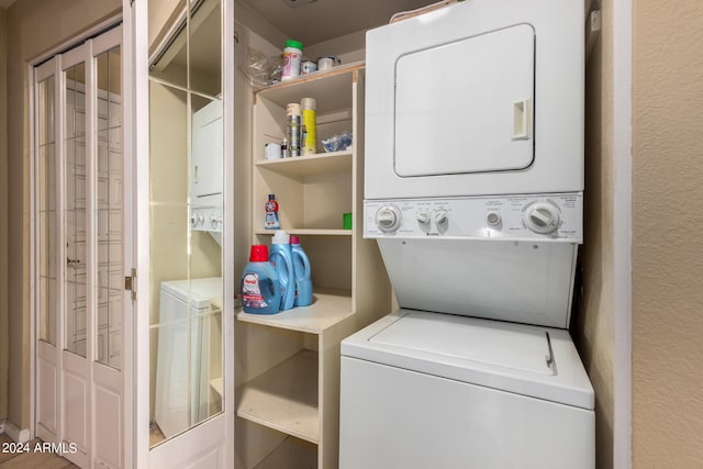 laundry room featuring laundry area, stacked washer / drying machine, and a textured wall