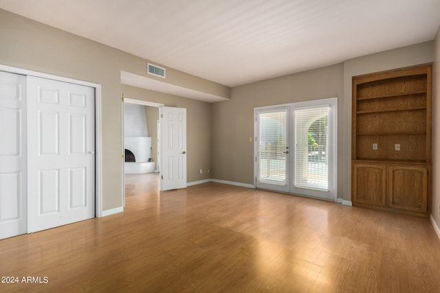 unfurnished living room with baseboards, visible vents, and wood finished floors