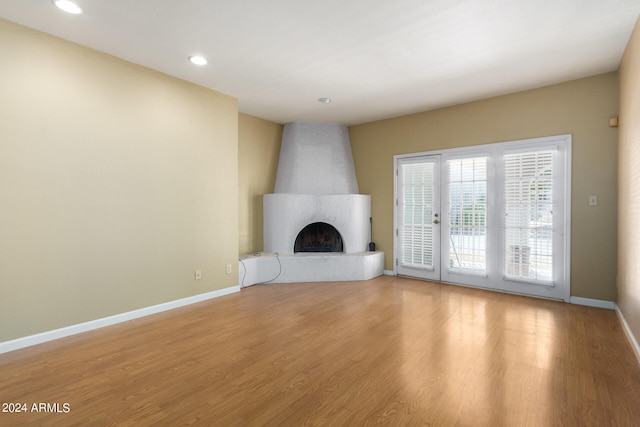 unfurnished living room with recessed lighting, light wood-type flooring, a fireplace, and baseboards