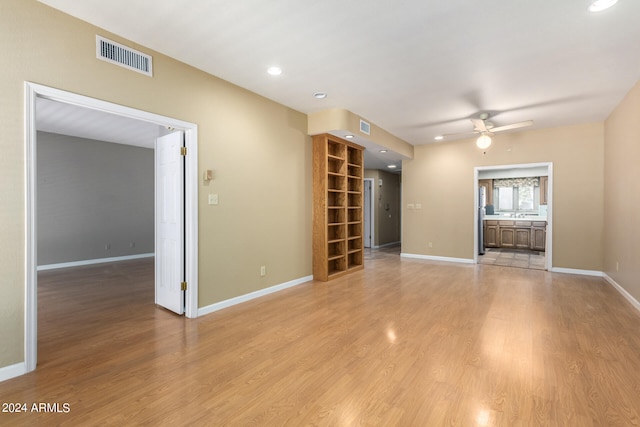 unfurnished living room with visible vents, ceiling fan, light wood-style flooring, and baseboards