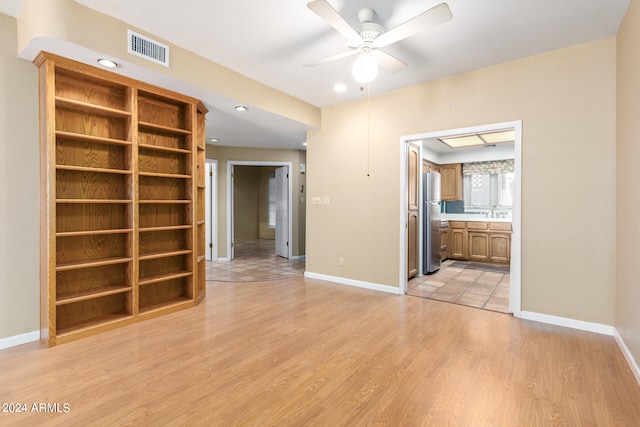 unfurnished room with baseboards, a ceiling fan, visible vents, and light wood-style floors