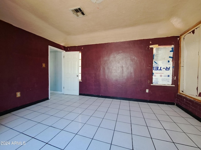 empty room with light tile patterned floors and a textured ceiling