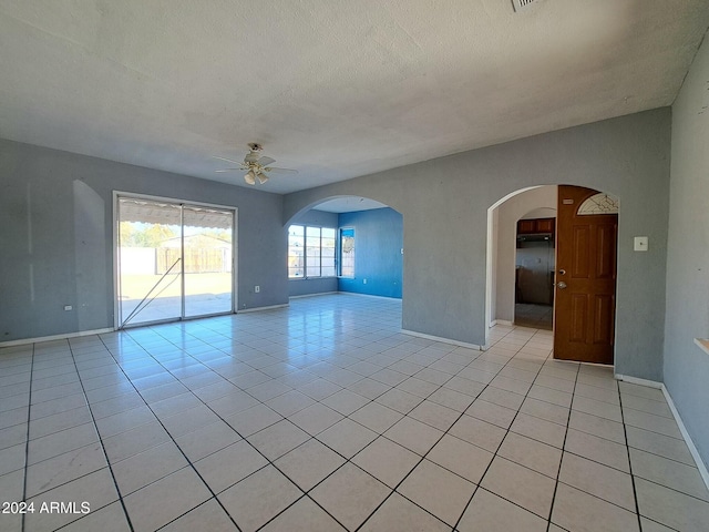 unfurnished room featuring ceiling fan, light tile patterned flooring, and a textured ceiling