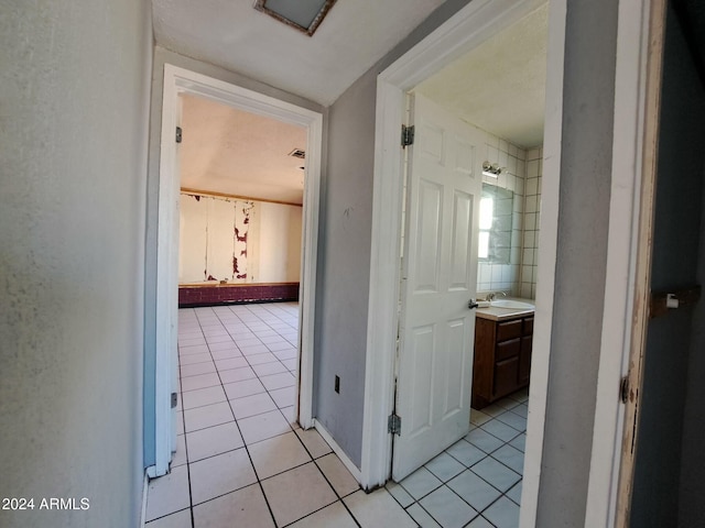 corridor featuring light tile patterned floors and sink