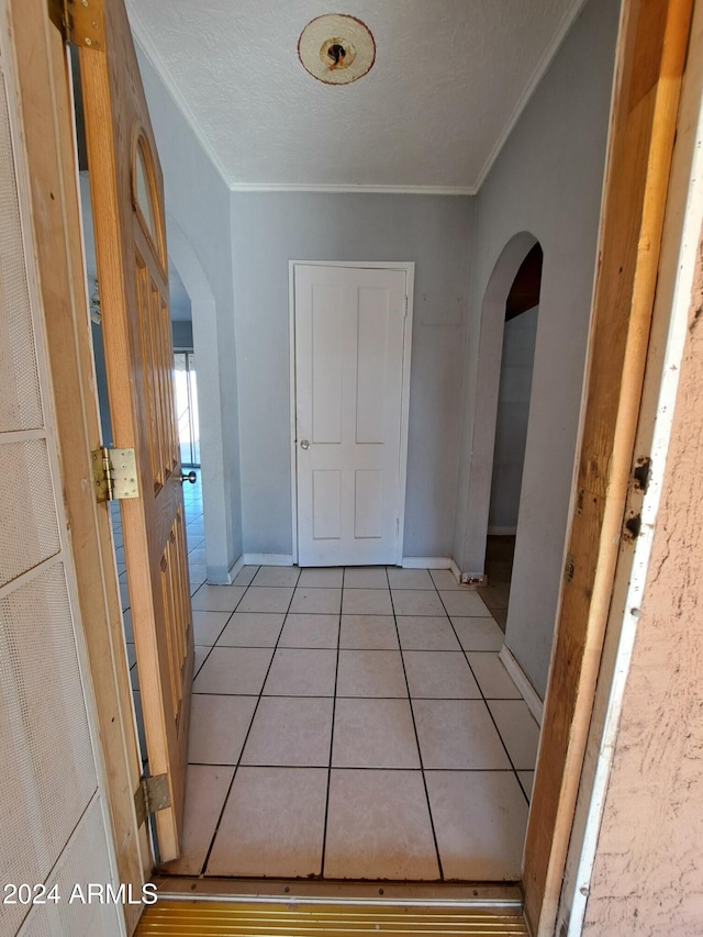 hallway with crown molding and light tile patterned flooring