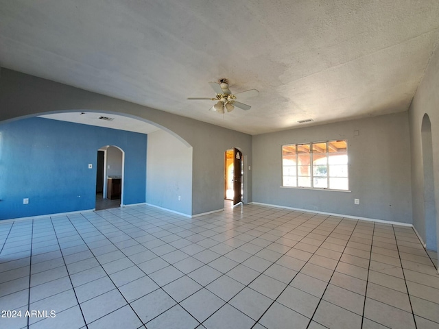 tiled empty room with ceiling fan and a textured ceiling