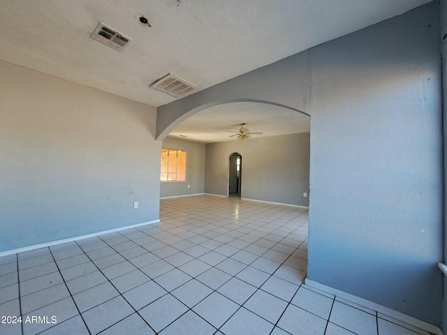 tiled empty room with ceiling fan and a textured ceiling