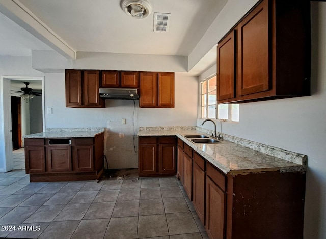 kitchen featuring tile patterned floors, ceiling fan, light stone counters, and sink