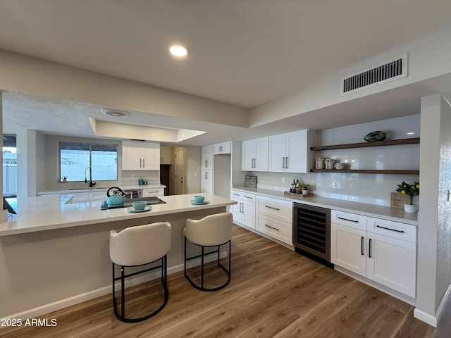 kitchen with white cabinetry, wine cooler, dark hardwood / wood-style flooring, a kitchen breakfast bar, and a tray ceiling