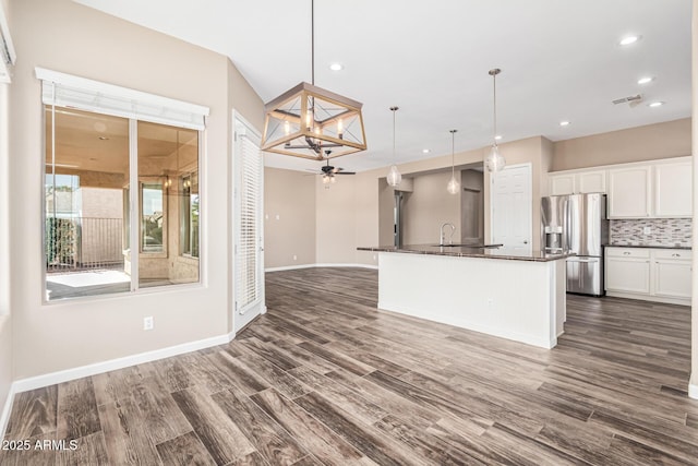 kitchen featuring pendant lighting, tasteful backsplash, white cabinetry, an island with sink, and stainless steel fridge with ice dispenser