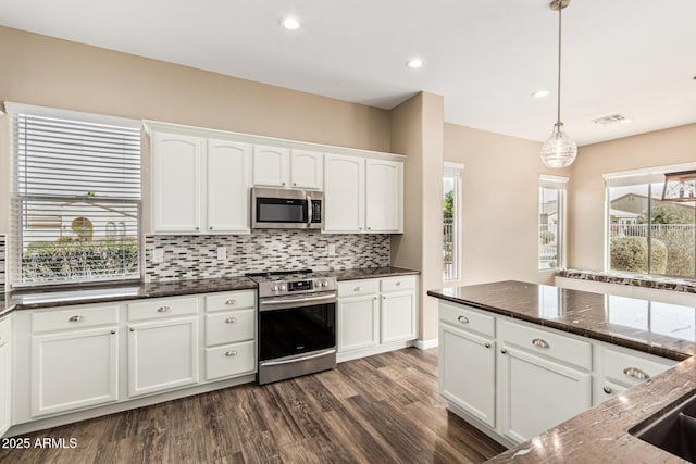 kitchen with white cabinetry, dark stone countertops, appliances with stainless steel finishes, pendant lighting, and backsplash